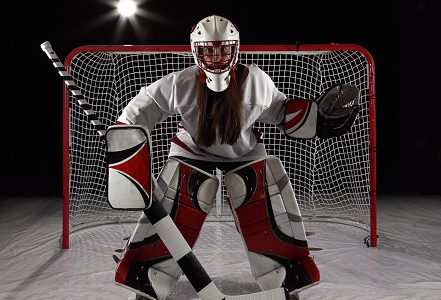 Young female goaltender in white jersey.